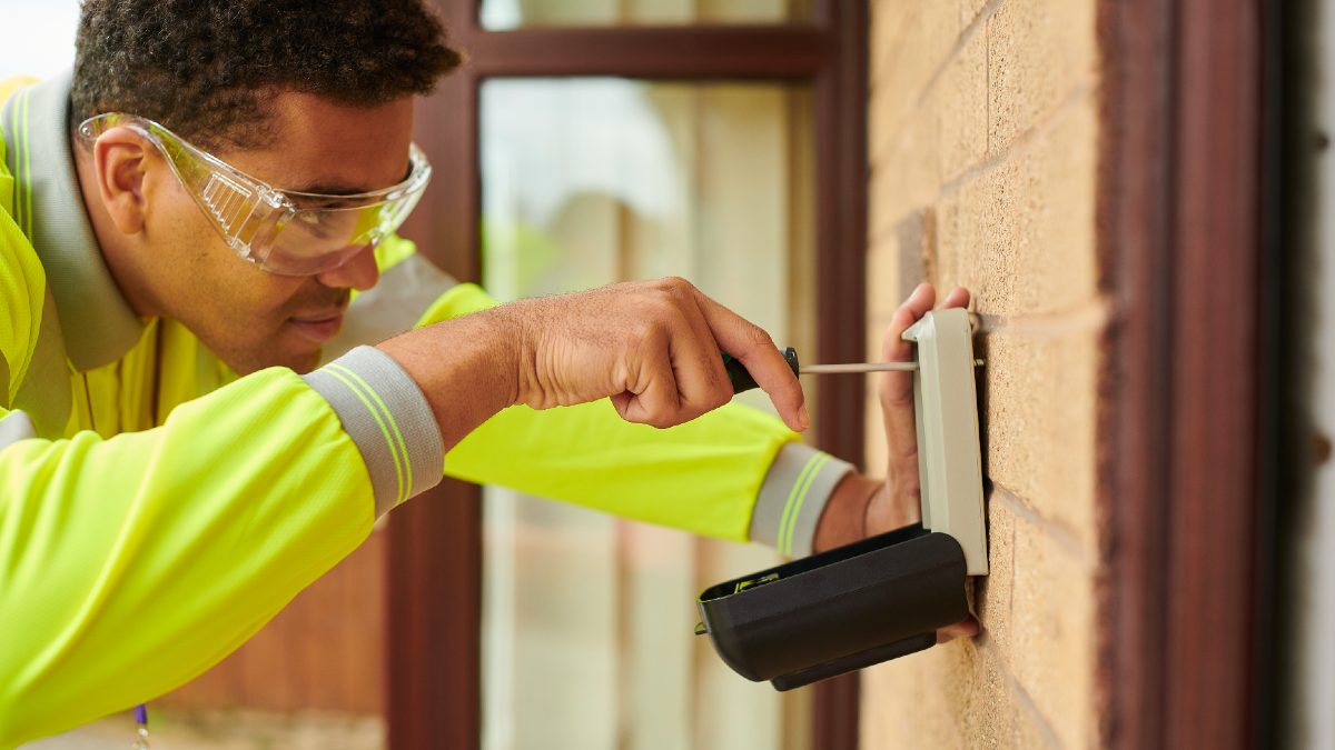 tradie installing key safe on exterior wall