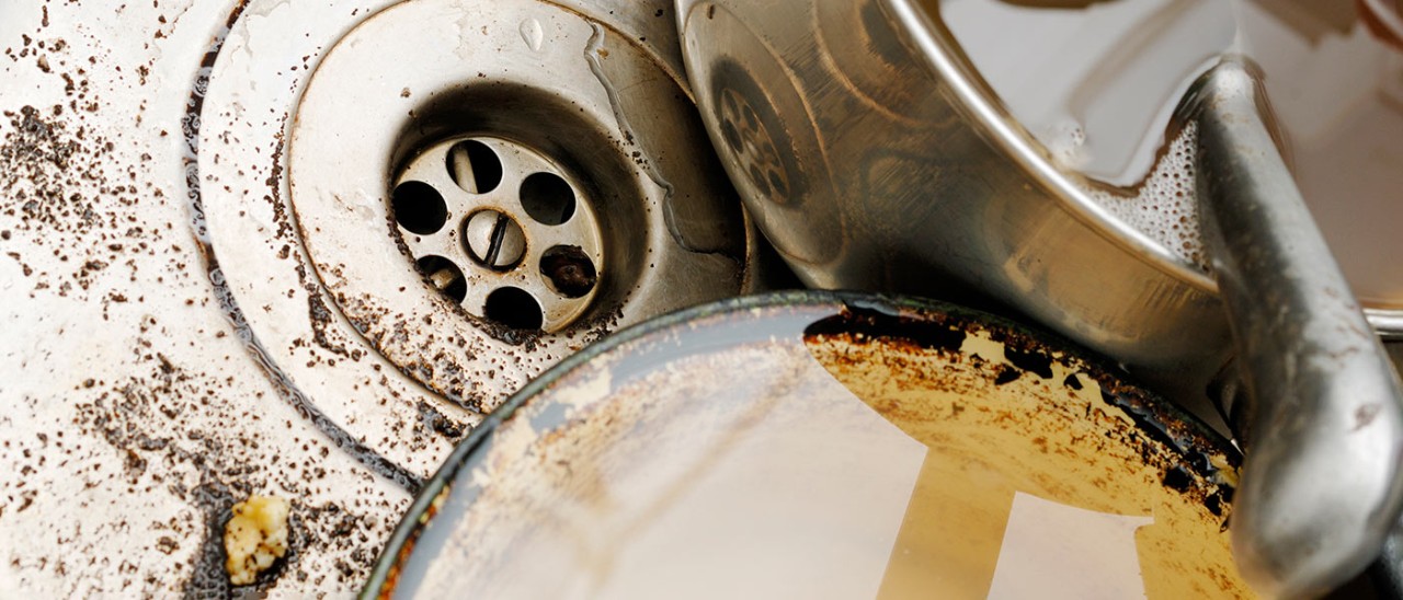 Close-up of two dirty saucepans in a sink.