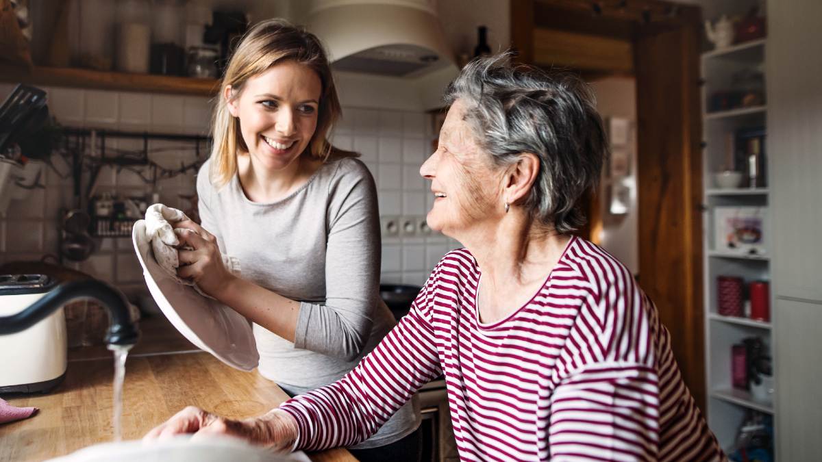 senior woman washing dishes with younger woman