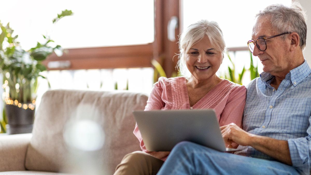 senior woman and man on couch looking at laptop together