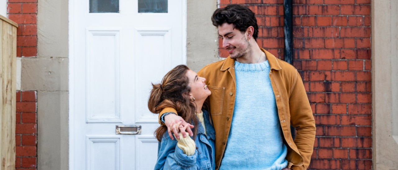 two young people outside their home