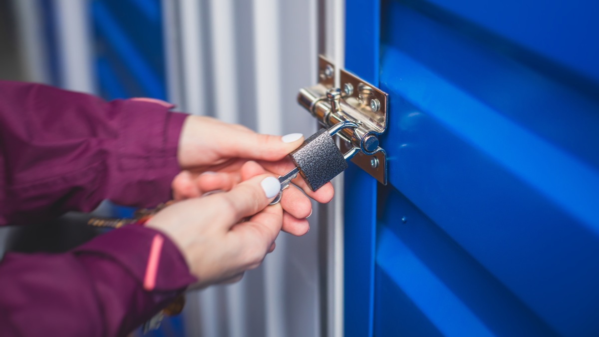 woman unlocking a padlock fixed to a blue garage door