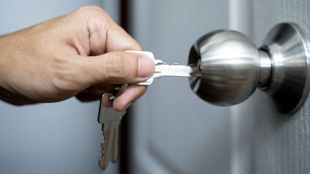 man unlocking a key in knob door