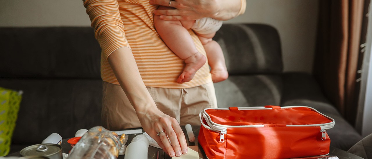 Mother holding baby and packing bushfire emergency kit