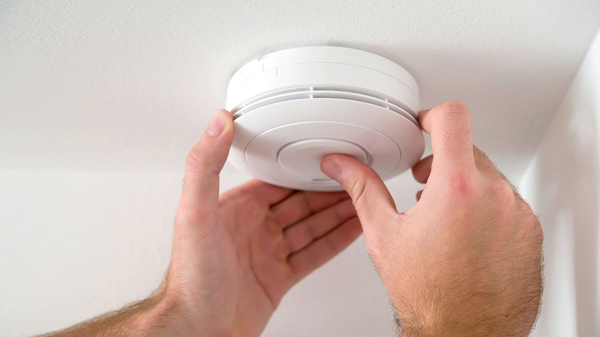 A person testing a smoke alarm
