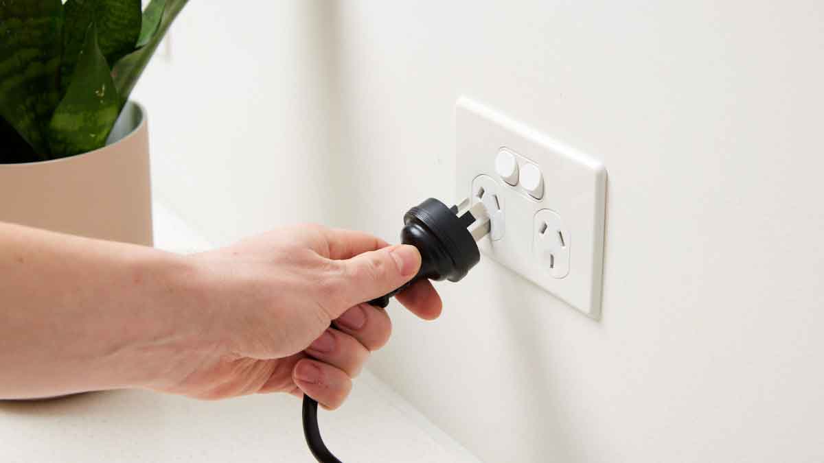 man plugging in cord to power point