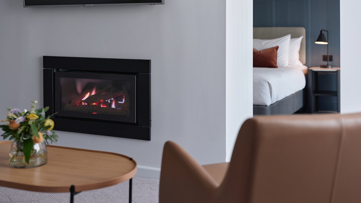 A gas log fireplace in a modern hotel room