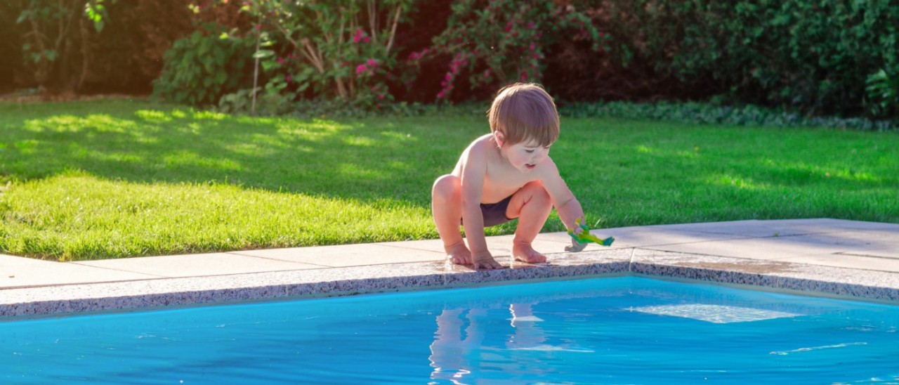 small boy leaning over swimming pool