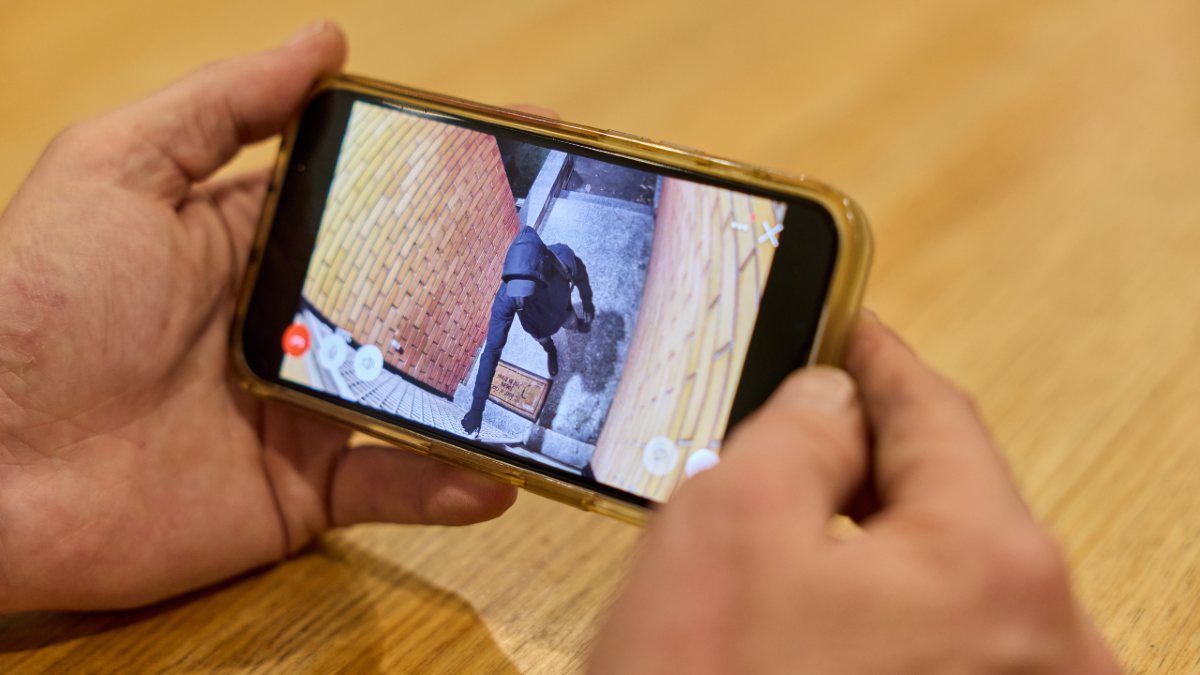 A person watching footage of the outside of their front door via a smartphone app
