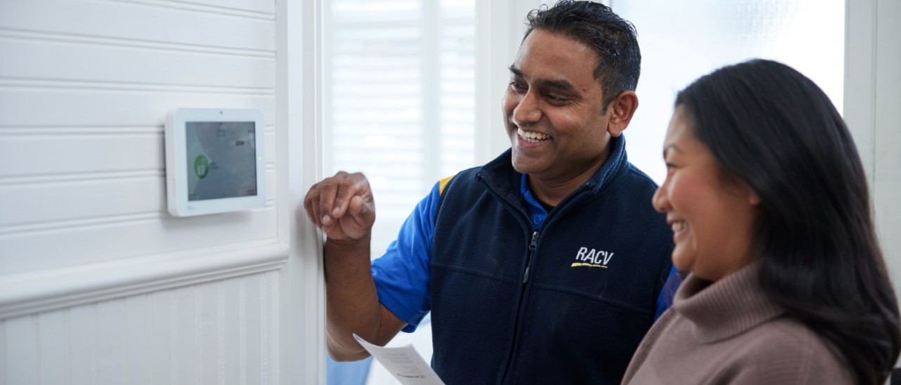 An RACV home security technician shows a woman how to use her new home security control panel