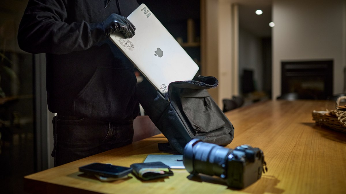 burglar stealing electronics like a laptop and camera