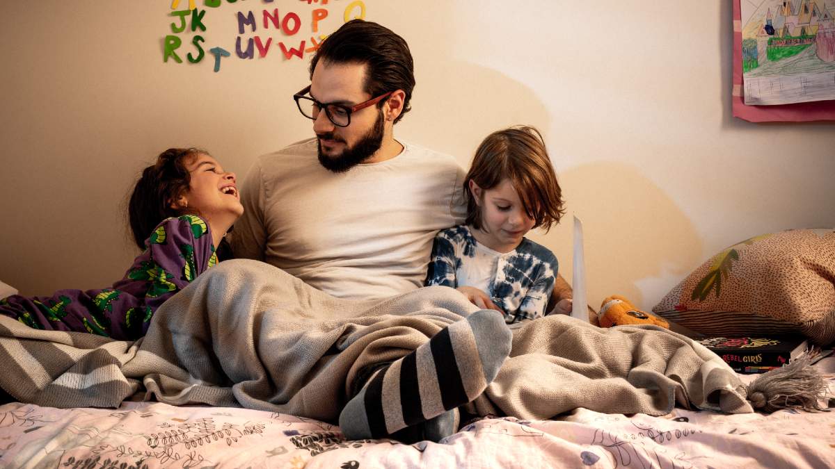 father with two young children on bed