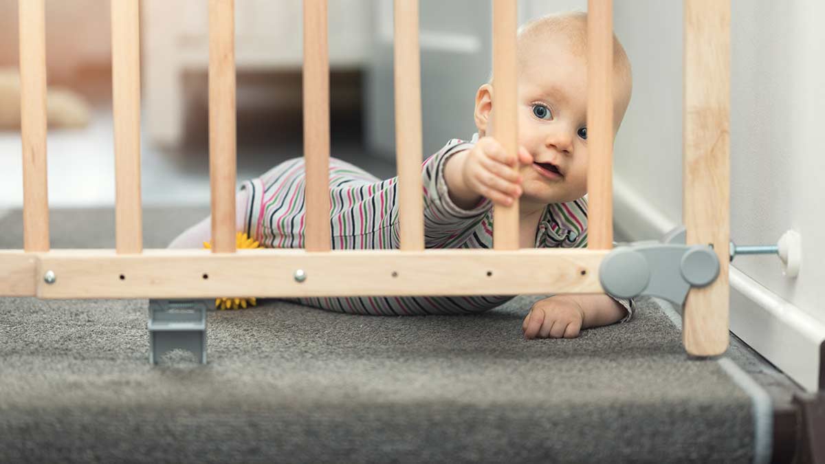 Child reaching through staircase baby gate