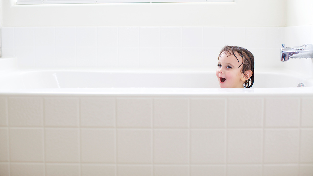 Toddler smiling in a bathtub