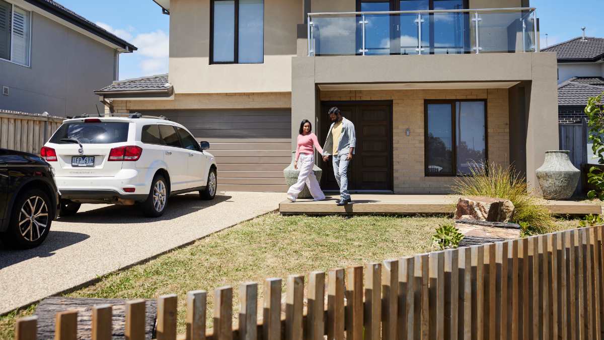 couple walking hand in hand down driveway with two parked cars