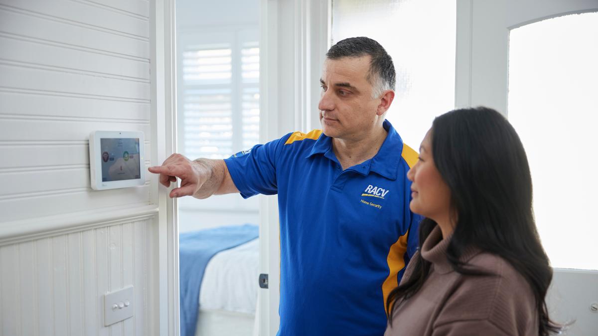 man showing woman how to operate home security system