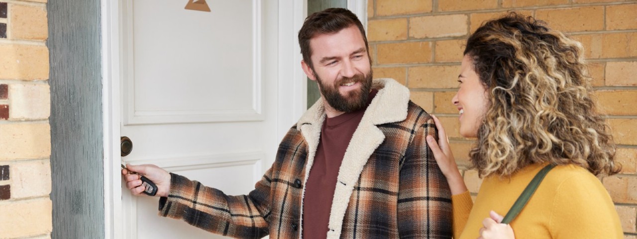 man locking front door with woman talking to him