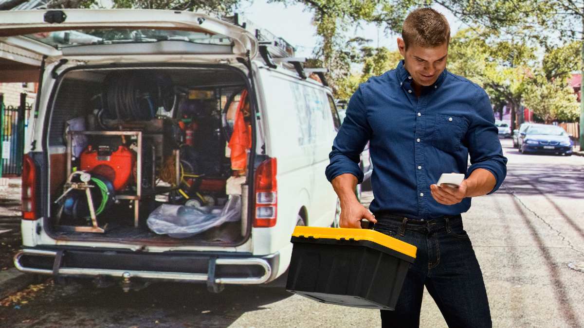 man walking away from an open work van carrying a toolbox