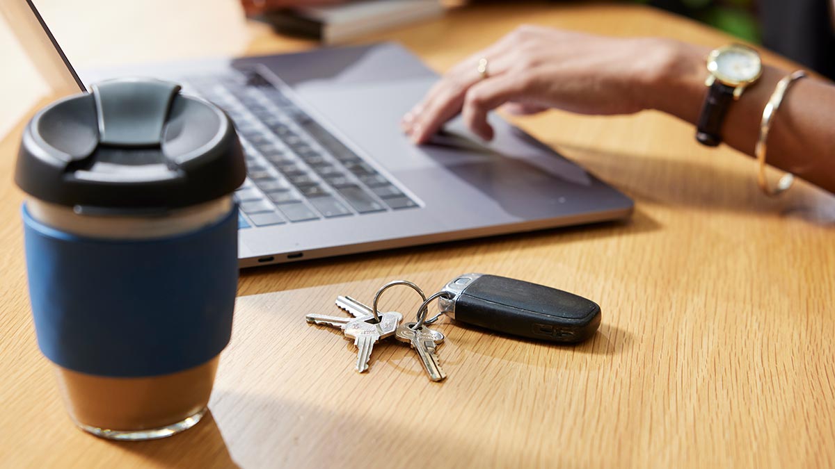 Woman at laptop computer with coffee and keys