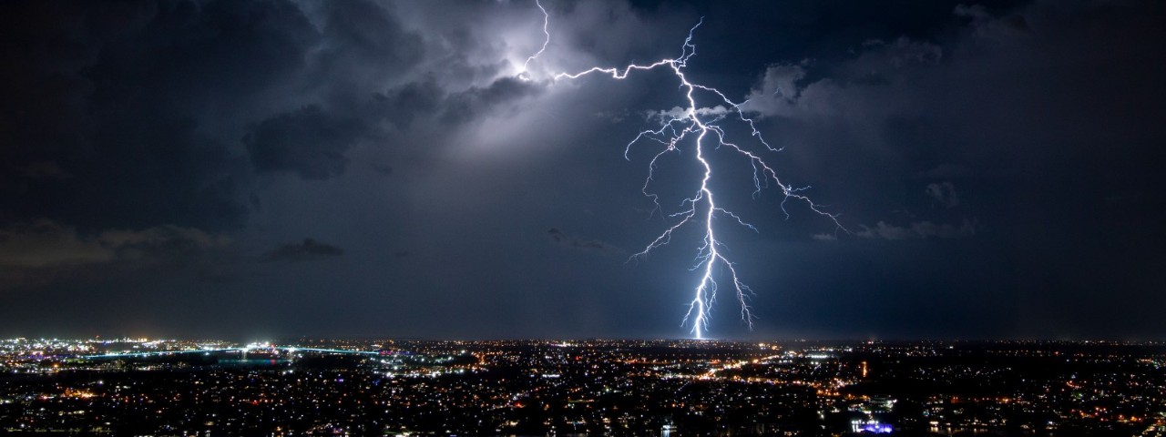 lightning strike from storm over city lights