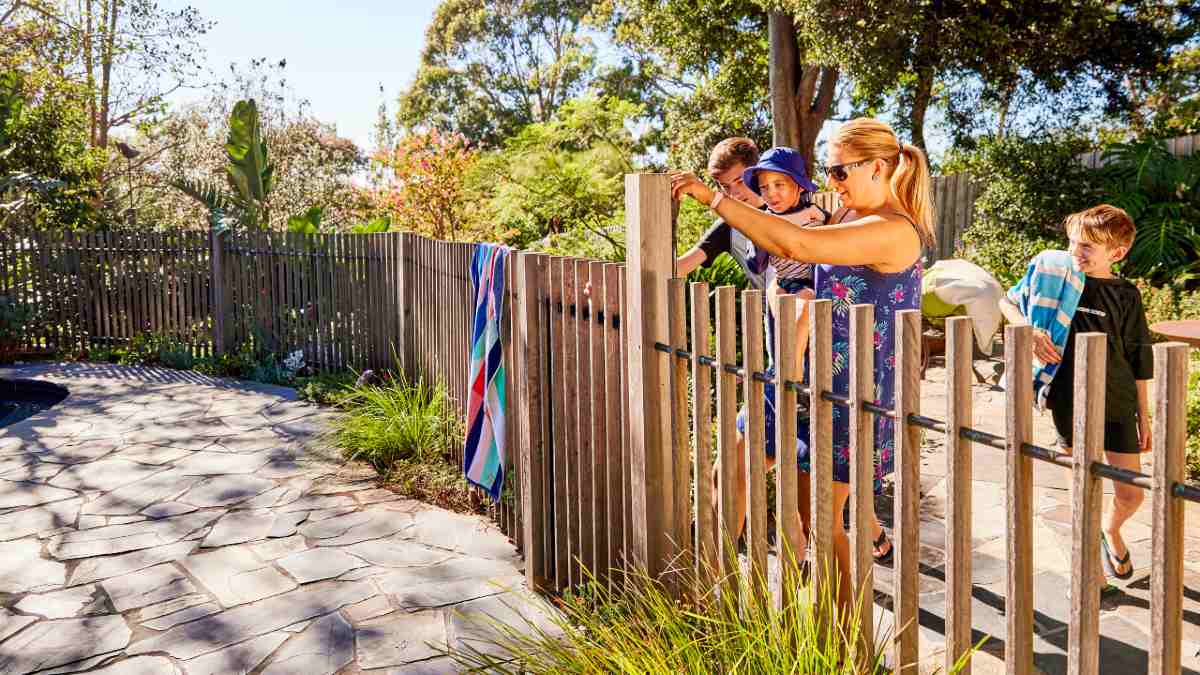 A mother opening a pool fence gate for her children