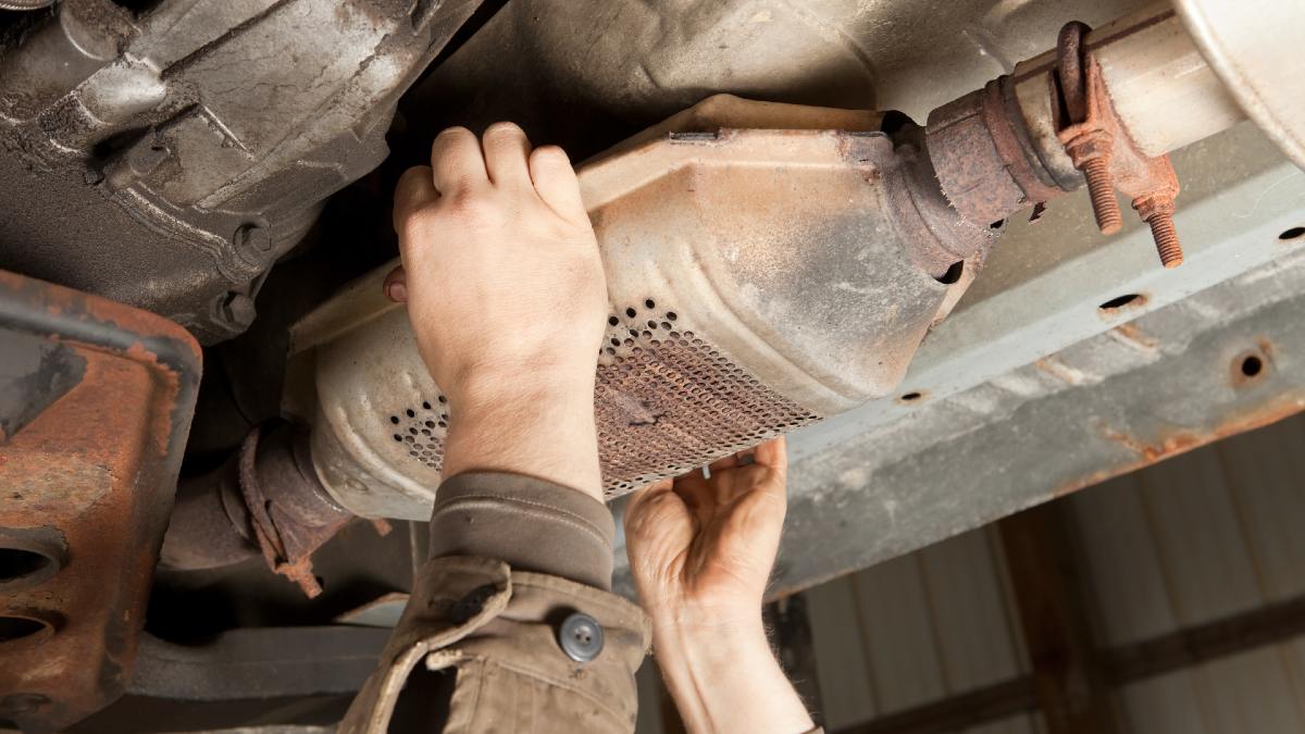 person removing a car exhaust system