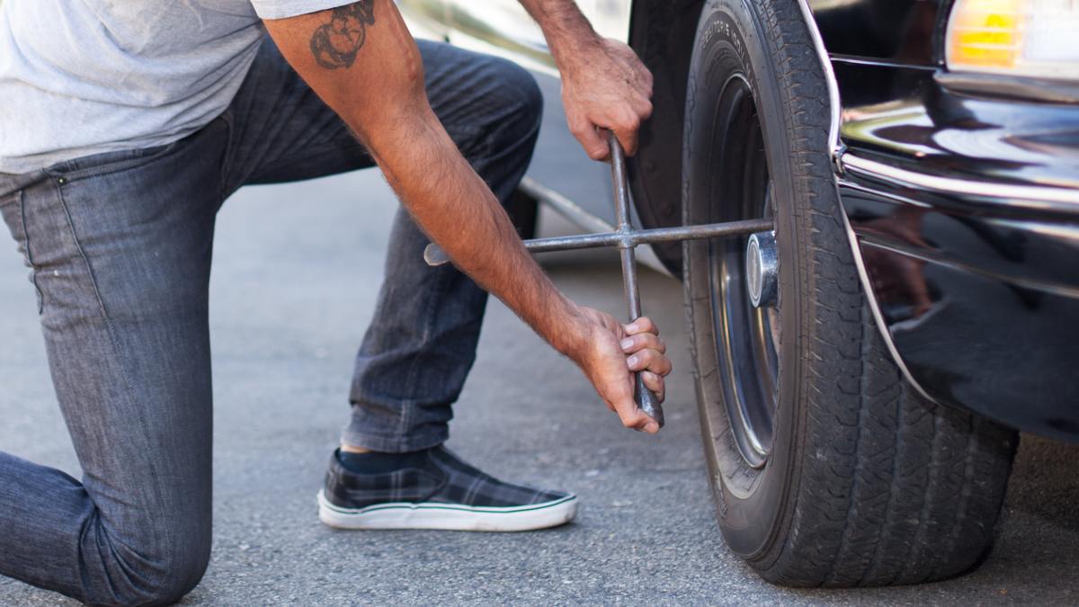 person removing a car tyre