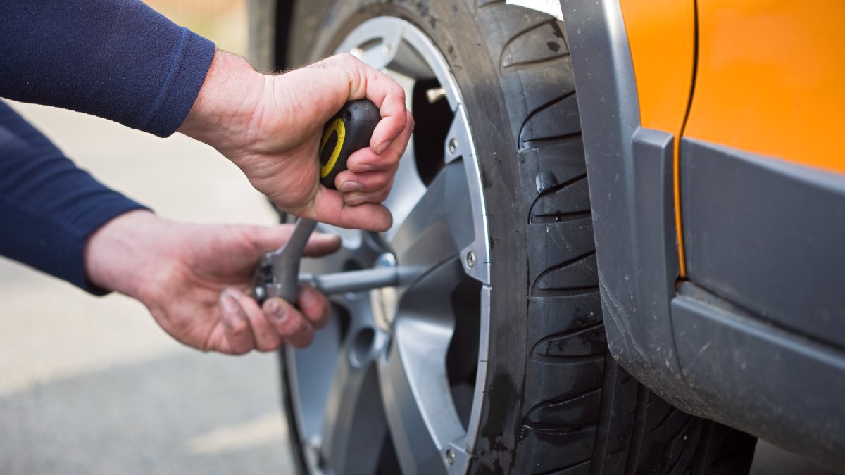 person removing wheel from car