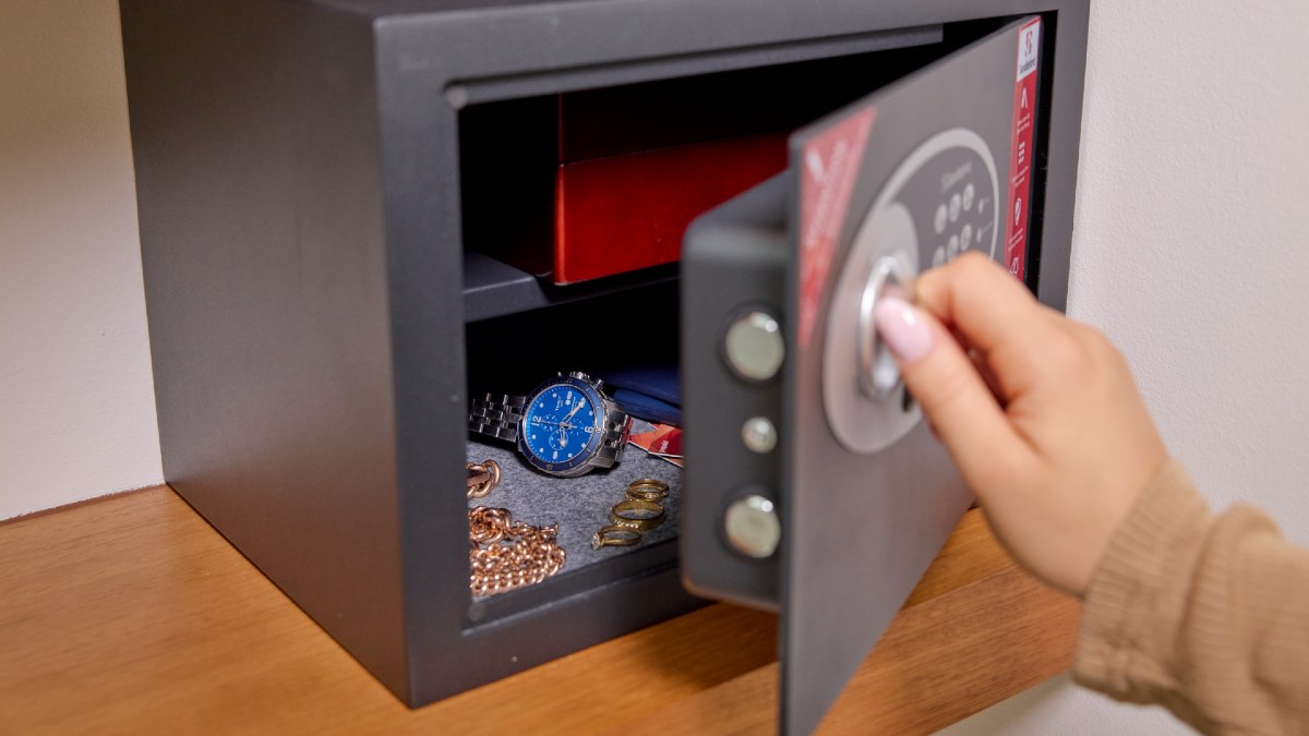 woman closing a home safe full of watches and jewellery