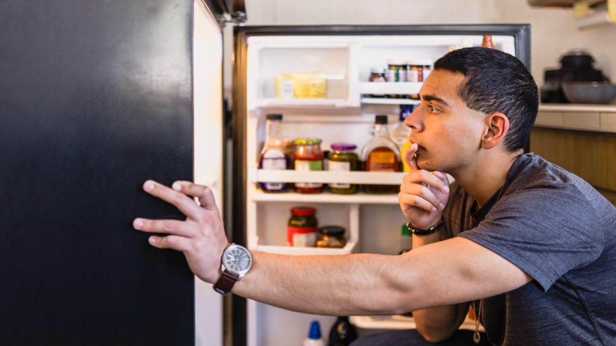 young man looking into his fridge