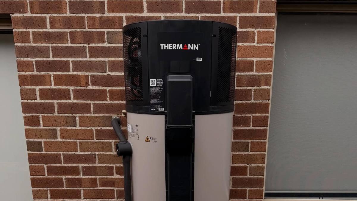 A Thermann heat pump hot water system installed next to a brick wall