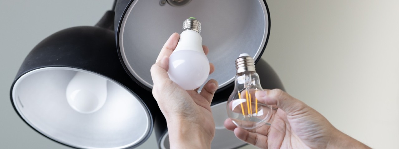person changing incandescent lightbulb to an LED globe