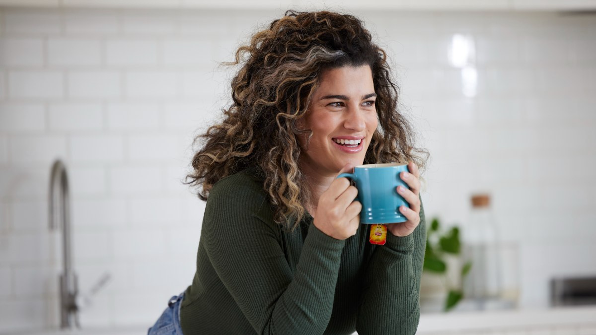 woman enjoying a cup of tea in her kitchen