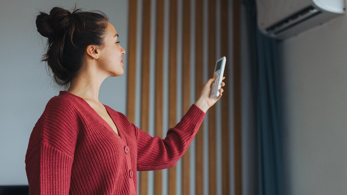 Woman adjusting temperature of air conditioning system