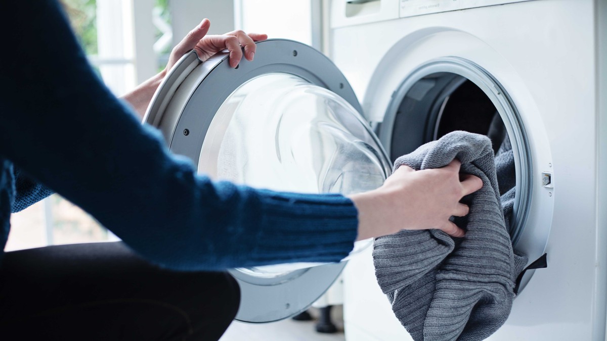 Person putting clothes in front loader washing machine