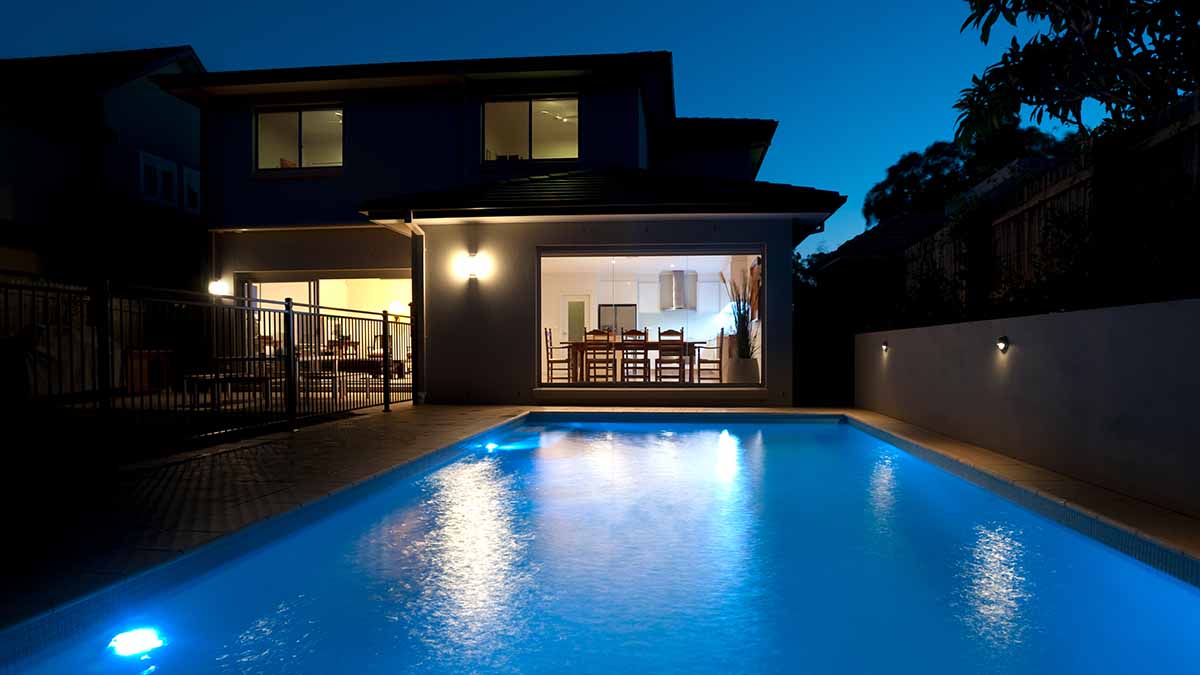 Backyard pool lit up at nightime.