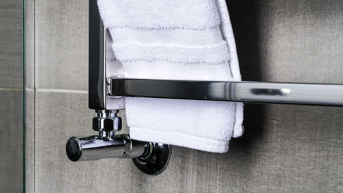 A white towel dries on a silver heated towel rail