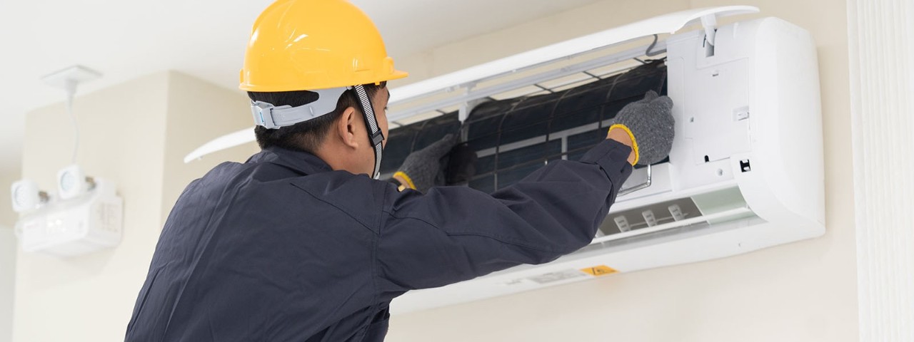 technician cleaning and servicing an air-conditioning unit