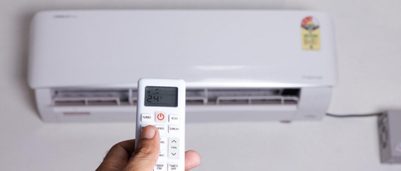 man turning on an air conditioner with its remote control