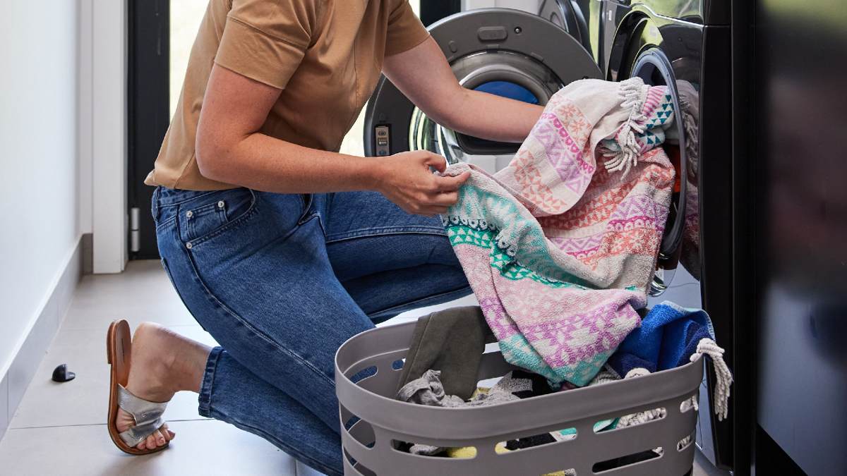 A person putting towels in a clothes dryer