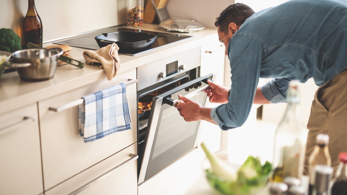 Man opening oven door in kitchen