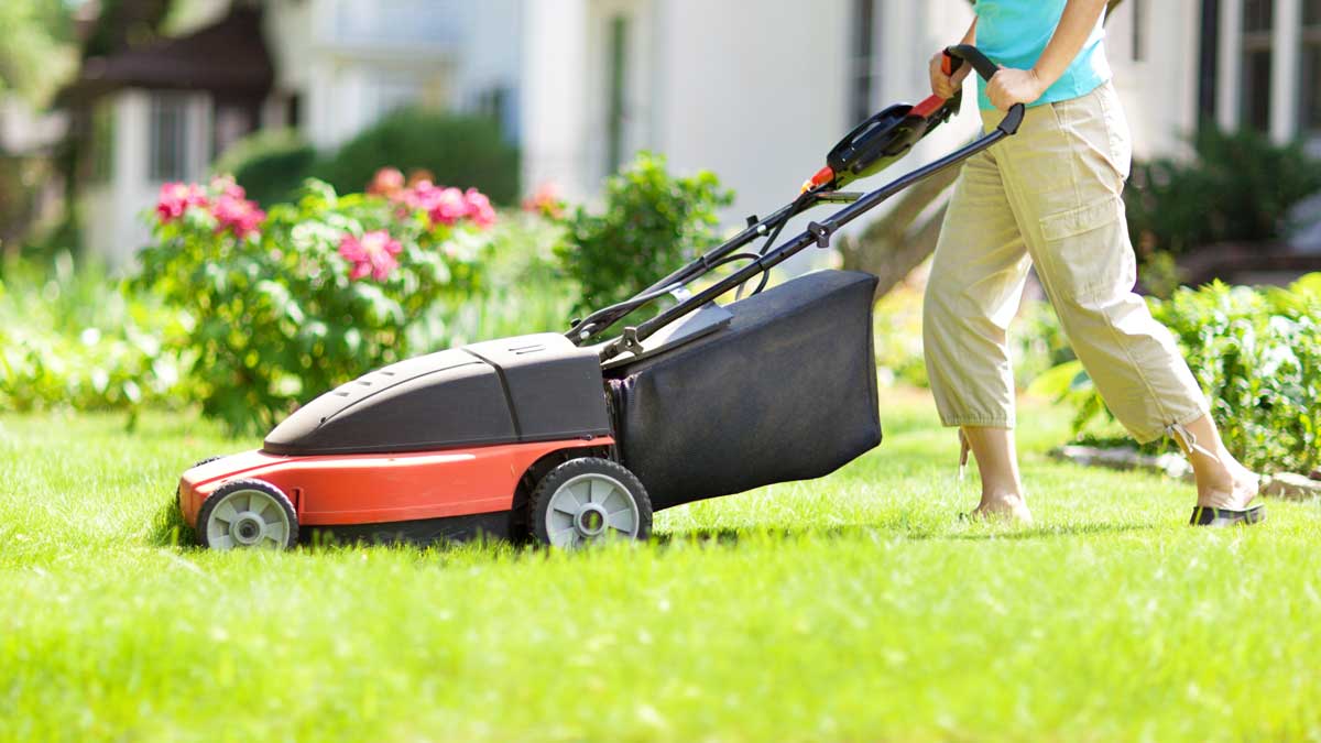 woman with electric lawn mower