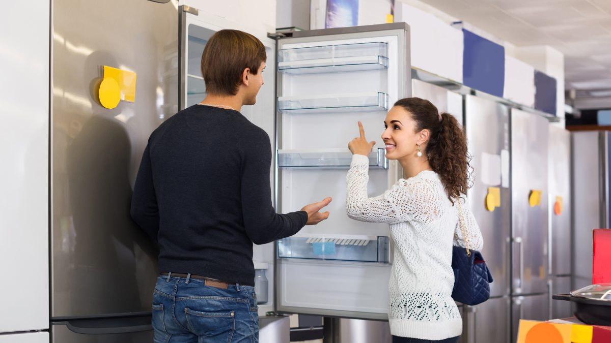 man and woman looking at new fridge in store