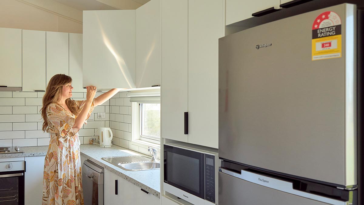 Woman opening a kitchen cupboard.