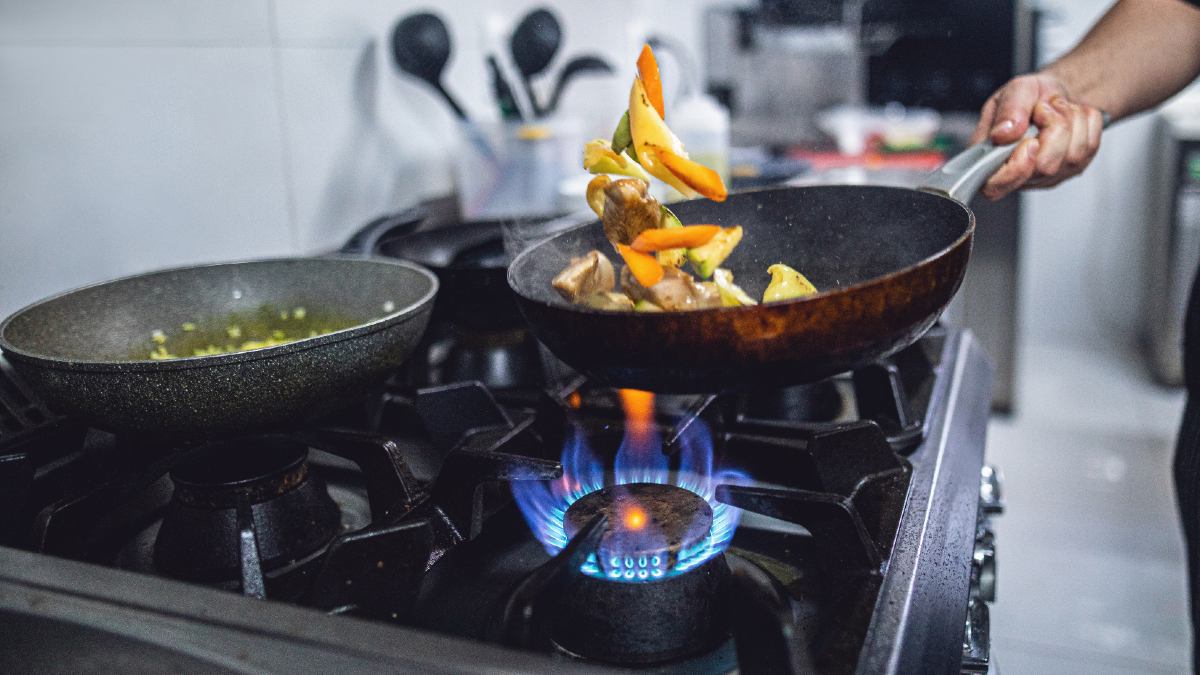 person cooking food on a gas cooktop