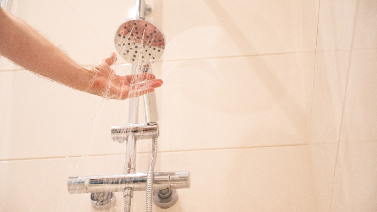 man checking temperature of shower