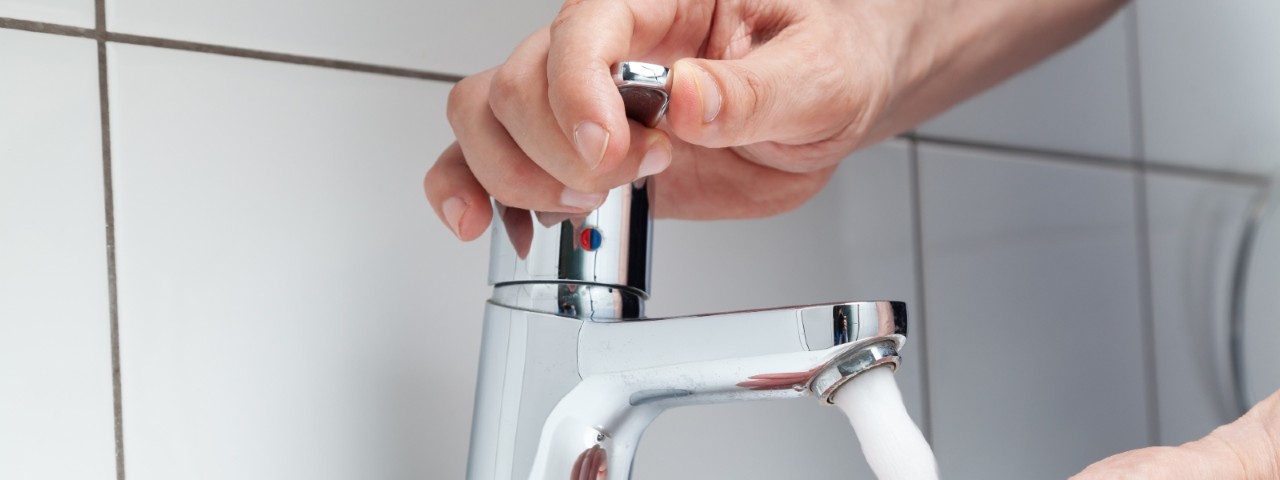 man turning hot water tap on