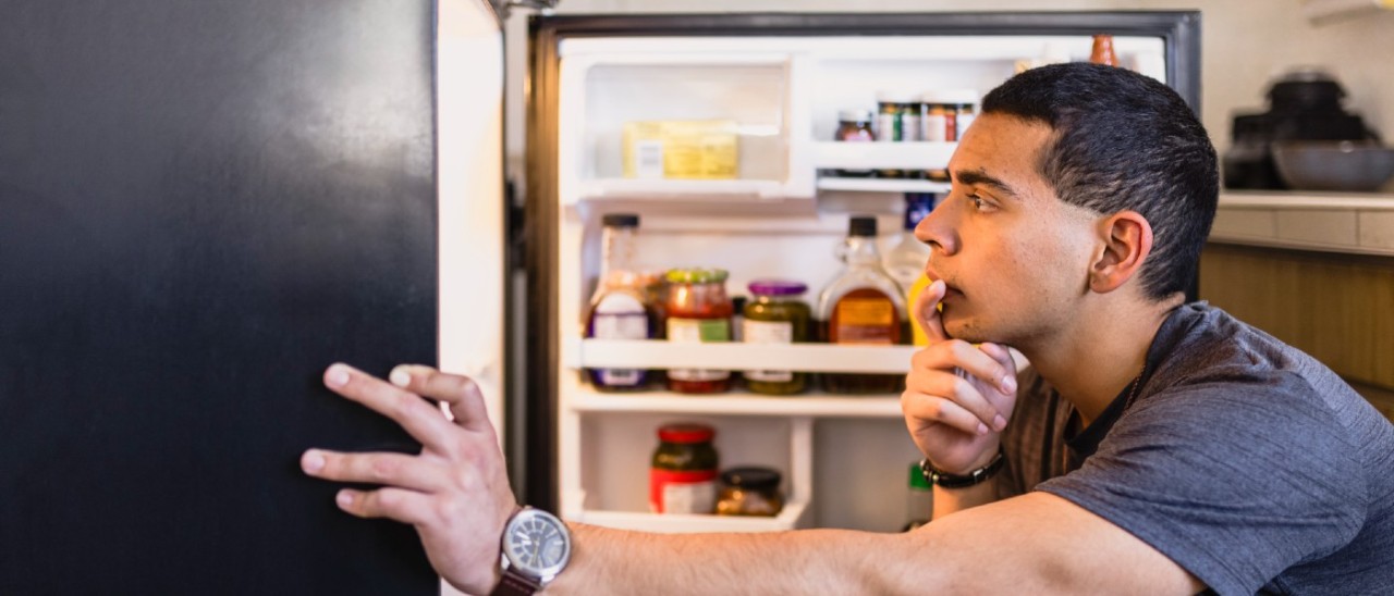 young man looking into his fridge