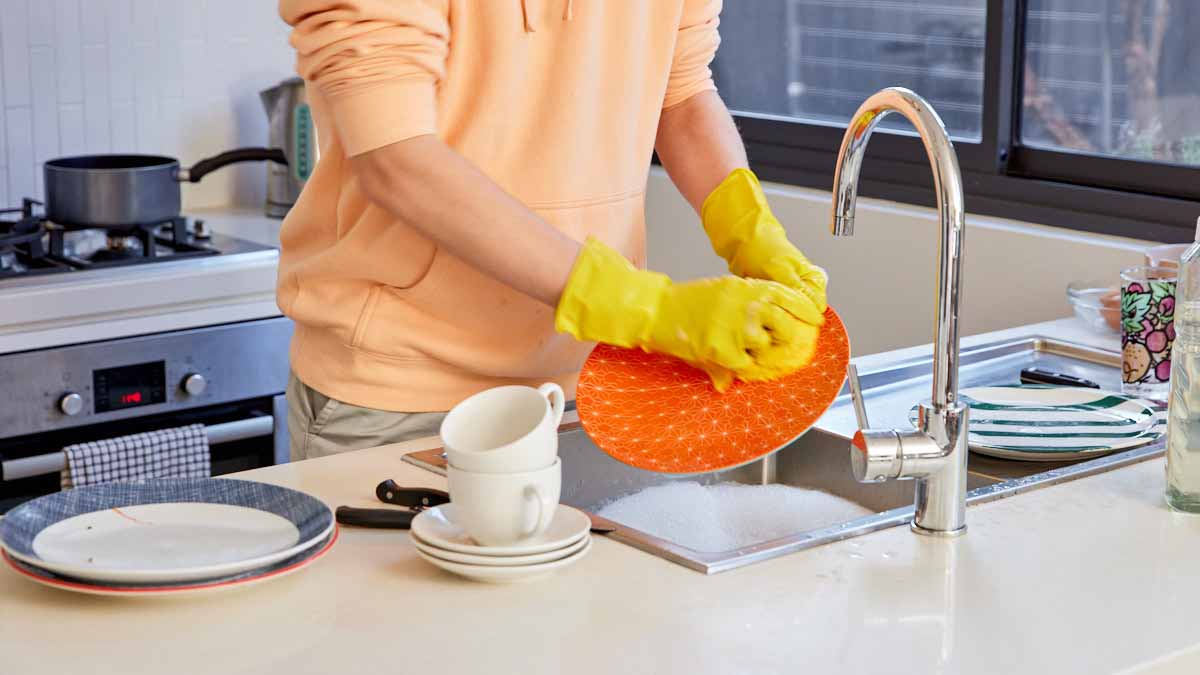 person washing up dishes at kitchen sink