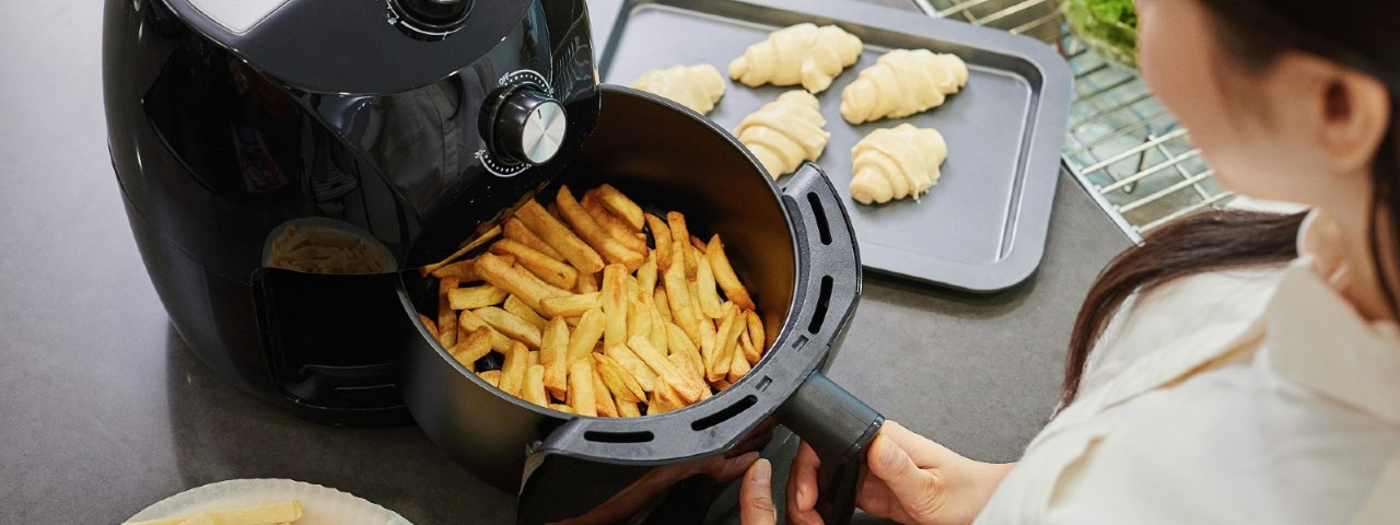 woman using air fryer to cook potato chips